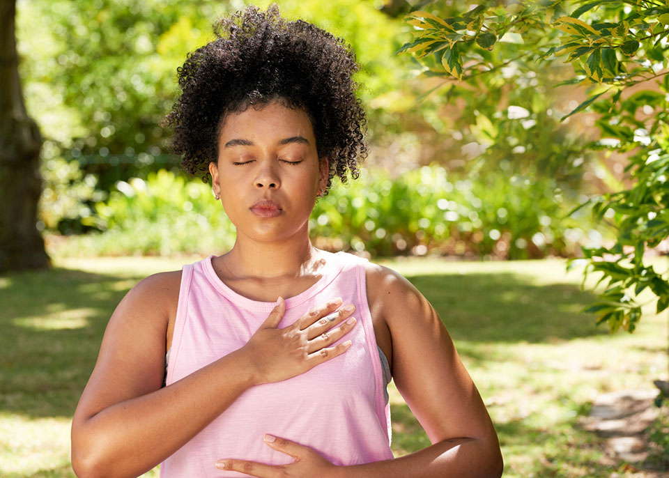 Young mutli-ethnic woman practices deep breathing in park